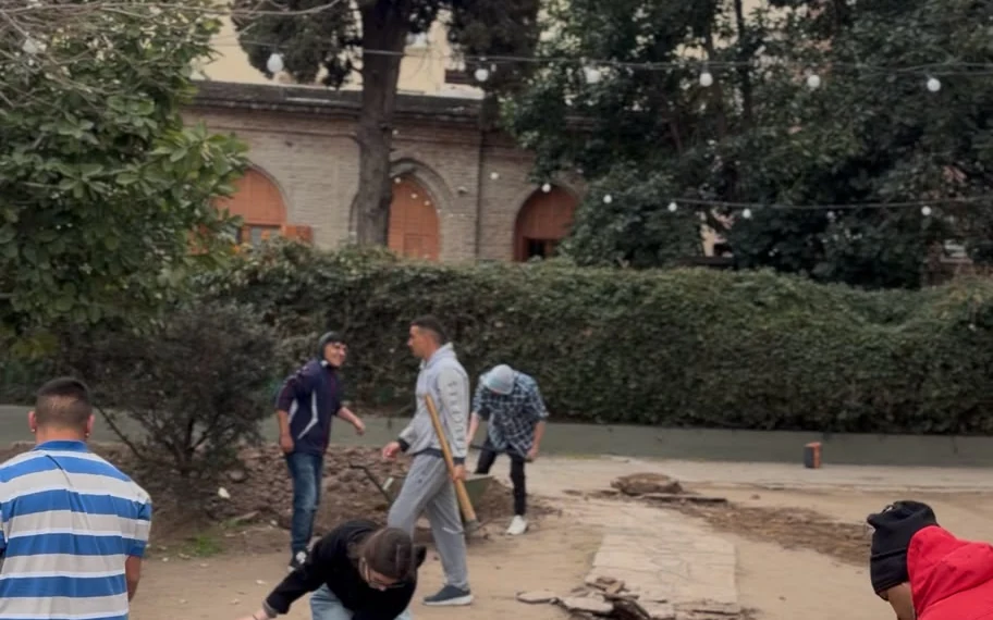 Chicos del Centro Barrial trabajando con carretilla y palas en el patio de la parroquia