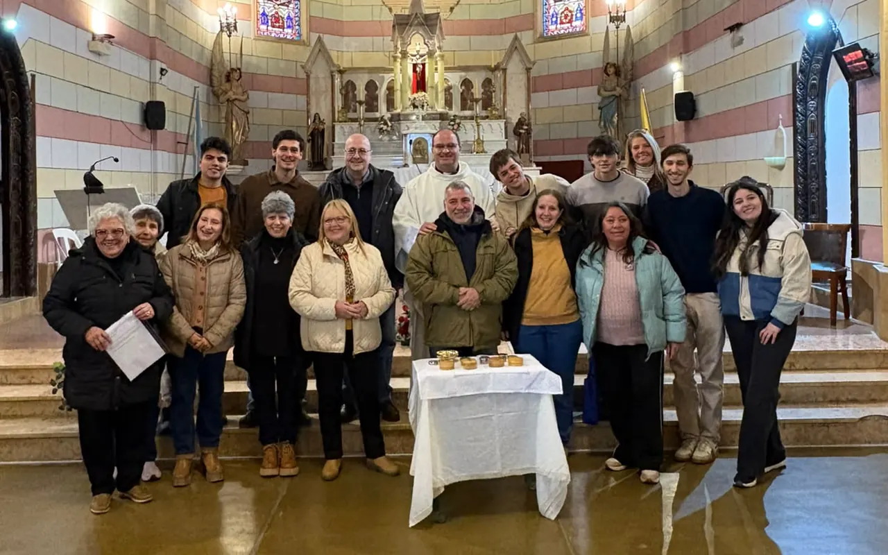 Los nuevos ministros extraordinarios de la comunion junto al parroco, frente al altar de la parroquia