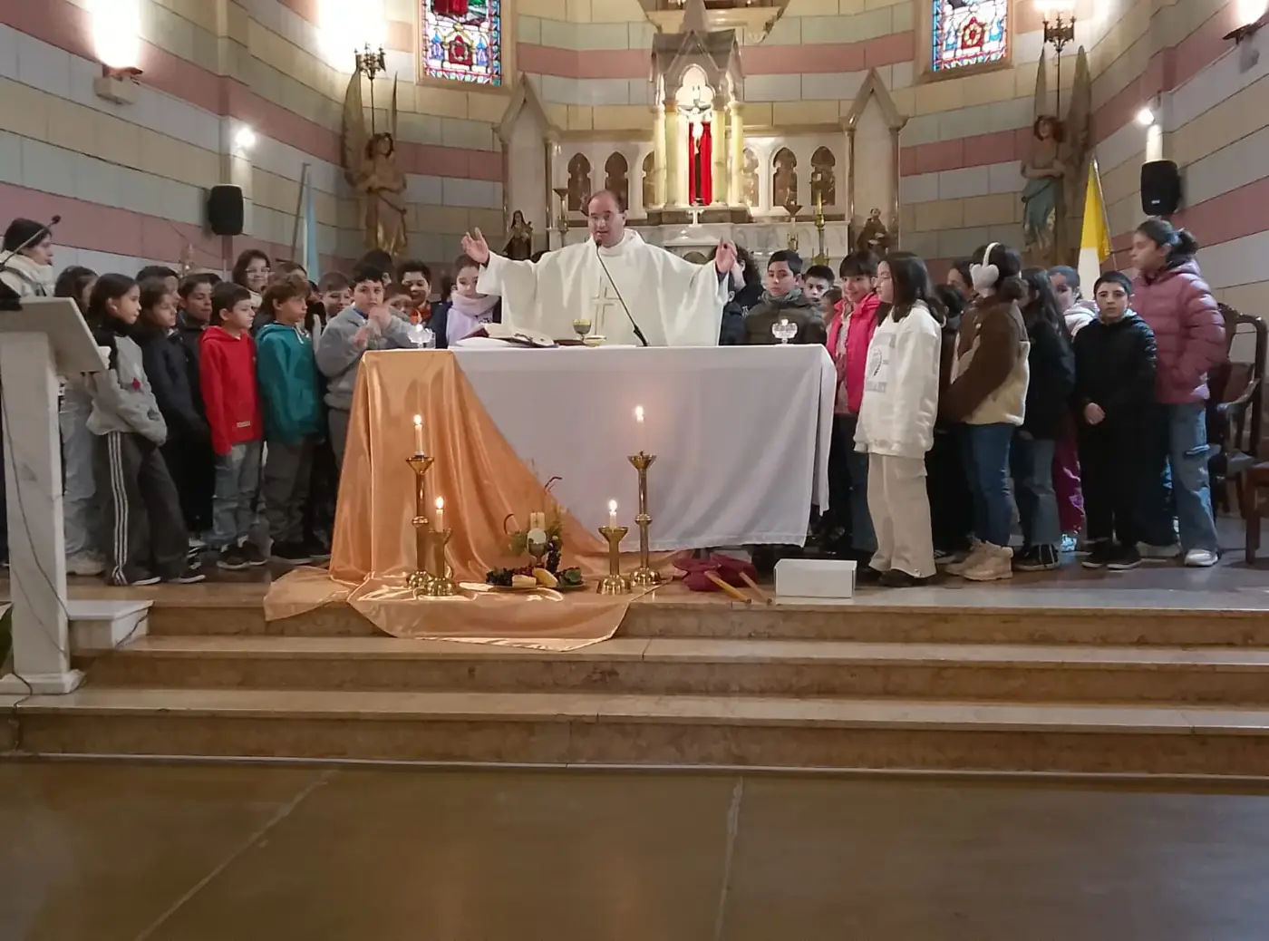 Misa con los chicos: los niños rodean el altar mientras el sacerdote extiende los brazos