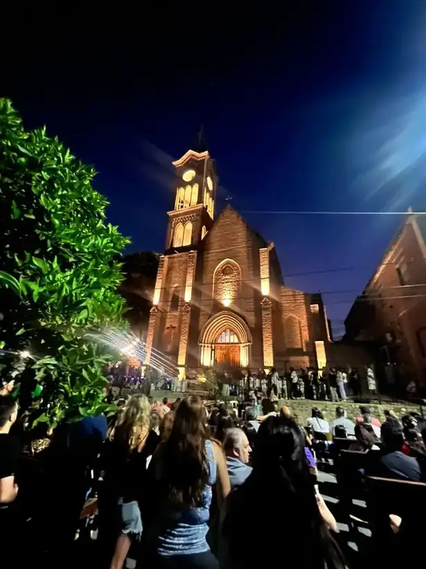 La comunidad reunida frente al templo iluminado al caer la noche