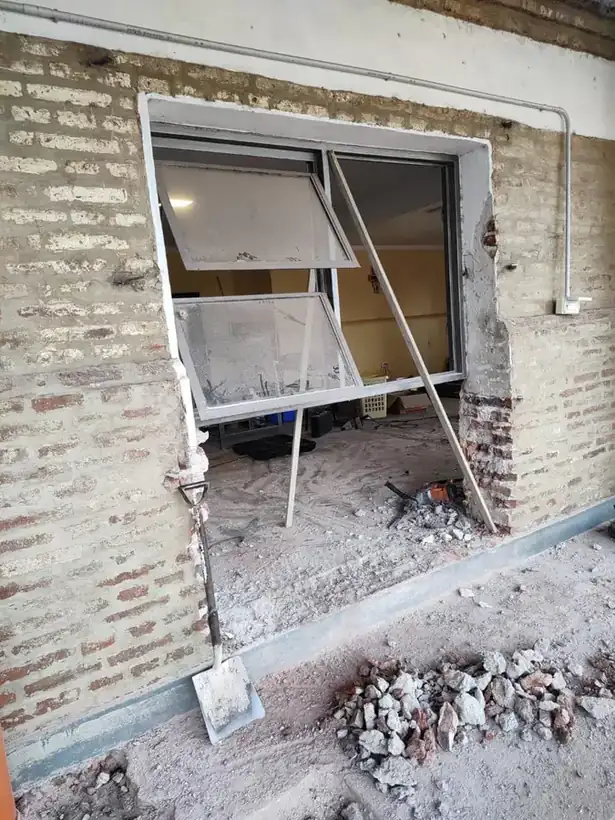 La pared de ladrillo abierta para colocar la ventana nueva, entre escombros