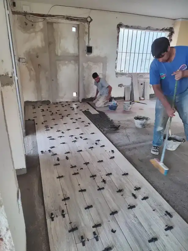Dos trabajadores terminando de asentar el piso del salón