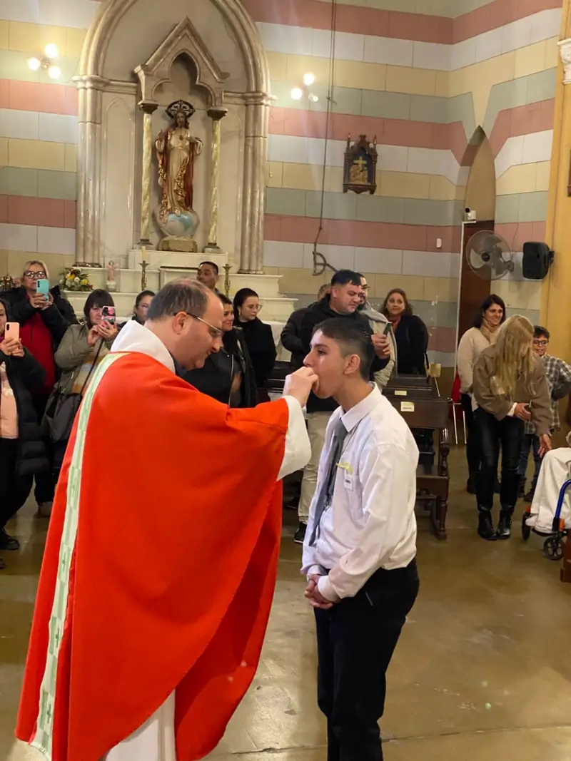 Un joven recibe la comunión de manos del párroco